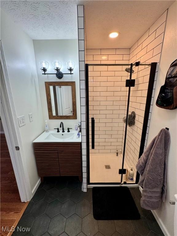 bathroom featuring an enclosed shower, vanity, tile patterned flooring, and a textured ceiling