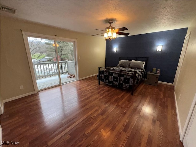 bedroom featuring ceiling fan, dark hardwood / wood-style floors, access to exterior, and a textured ceiling