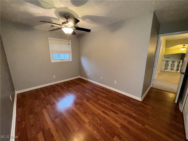 empty room with a textured ceiling, dark wood-type flooring, and ceiling fan