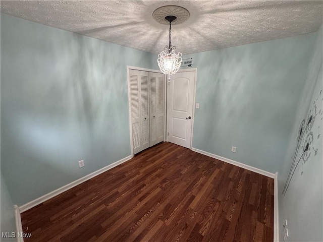 unfurnished room with dark hardwood / wood-style flooring, a textured ceiling, and an inviting chandelier