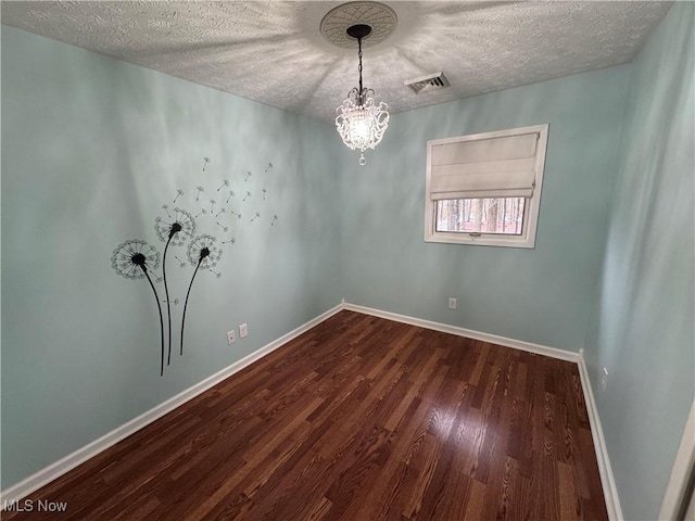 spare room with hardwood / wood-style flooring, a textured ceiling, and a notable chandelier