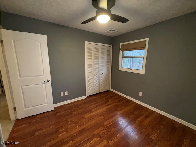 unfurnished bedroom featuring ceiling fan, dark hardwood / wood-style flooring, a closet, and a textured ceiling