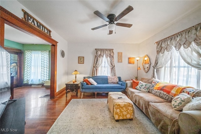 living room featuring ceiling fan, wood-type flooring, and a wealth of natural light