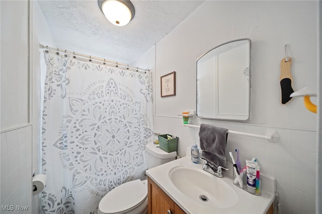 bathroom featuring tile walls, vanity, toilet, a textured ceiling, and a shower with curtain