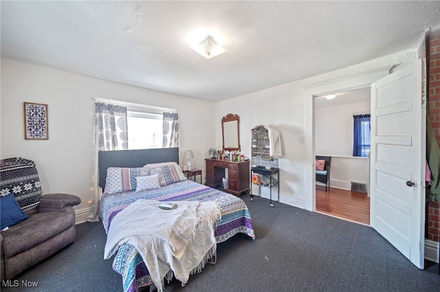 bedroom with dark colored carpet and a textured ceiling