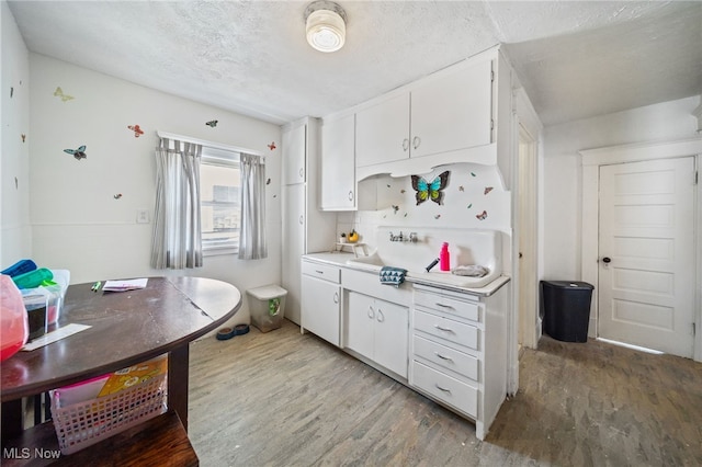 kitchen featuring white cabinetry, a textured ceiling, and light wood-type flooring