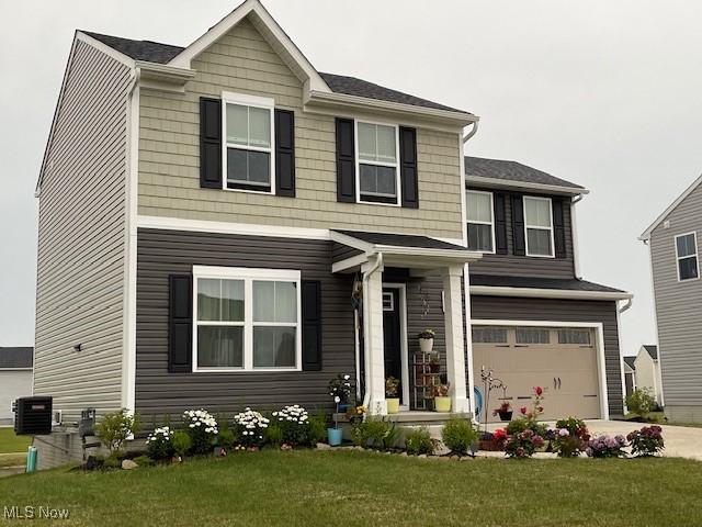 view of front of property with a garage, central AC unit, and a front lawn