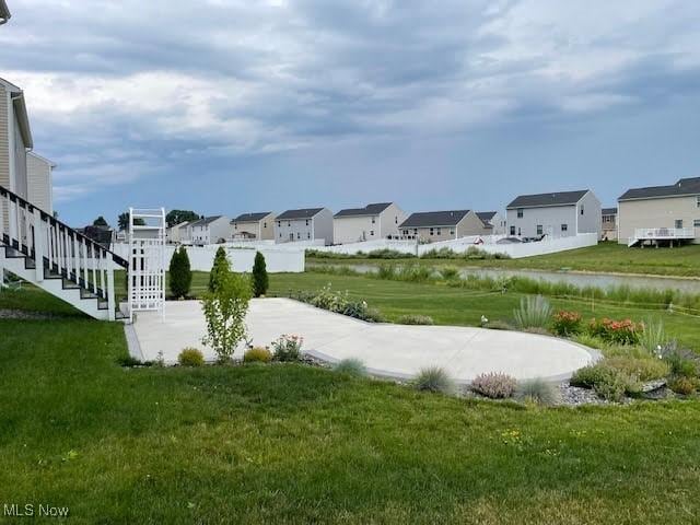 view of home's community with a water view and a lawn