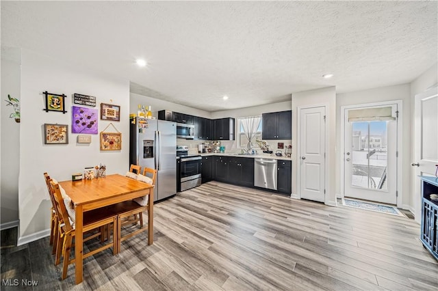 kitchen with sink, stainless steel appliances, a textured ceiling, and light wood-type flooring