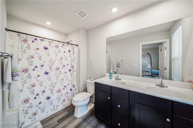 bathroom with wood-type flooring, a shower with shower curtain, vanity, and toilet