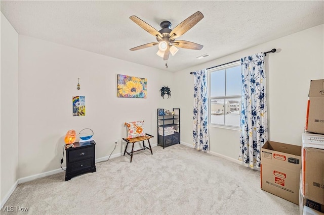 game room with ceiling fan, light colored carpet, and a textured ceiling