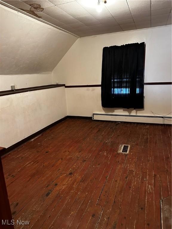 additional living space with vaulted ceiling, hardwood / wood-style floors, and baseboard heating