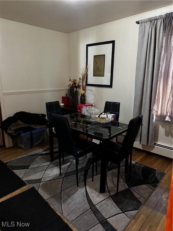 dining room with wood-type flooring and a baseboard heating unit