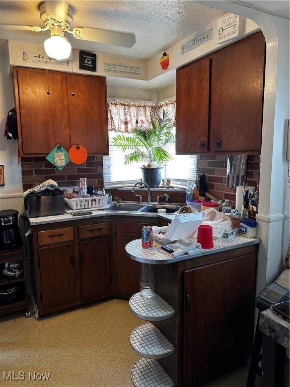 kitchen featuring sink, backsplash, a textured ceiling, and ceiling fan