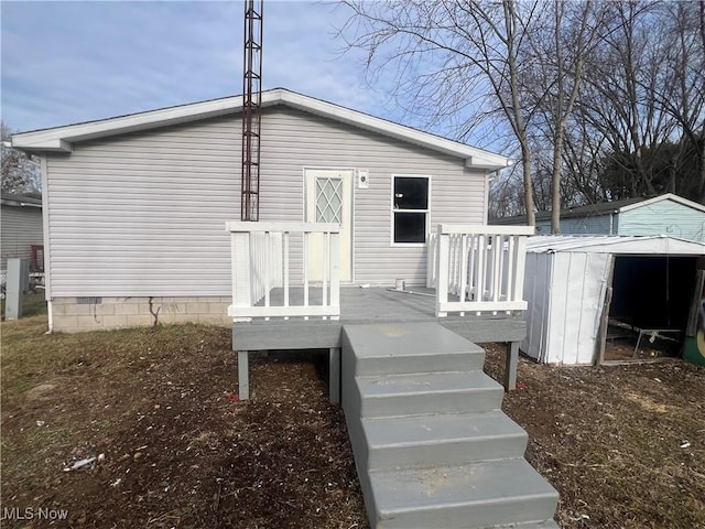 rear view of property featuring a wooden deck and a storage shed