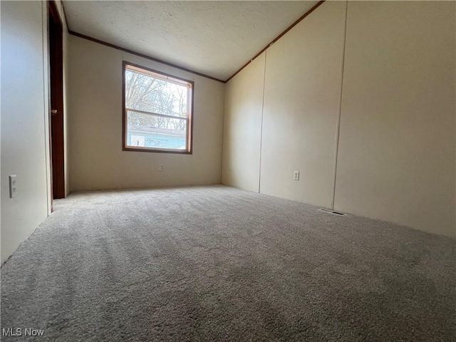 carpeted spare room featuring vaulted ceiling and ornamental molding