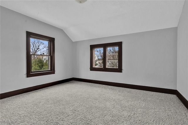 carpeted empty room with lofted ceiling