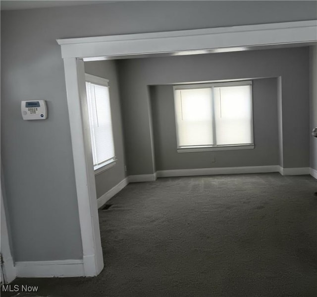 spare room featuring dark colored carpet