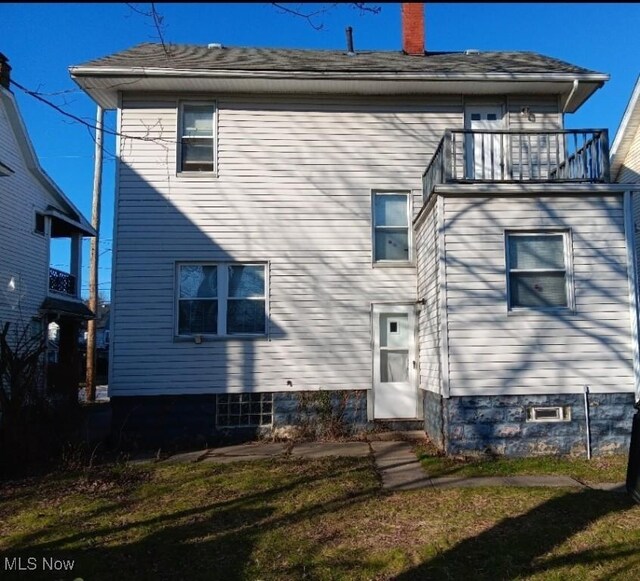 rear view of house featuring a lawn and a balcony