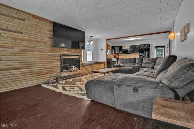 living room featuring a brick fireplace, dark hardwood / wood-style floors, and brick wall