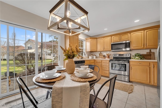 kitchen featuring light tile patterned flooring, sink, a chandelier, stainless steel appliances, and decorative backsplash