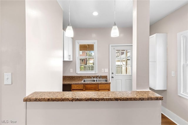 kitchen featuring sink, decorative light fixtures, dark hardwood / wood-style floors, and kitchen peninsula