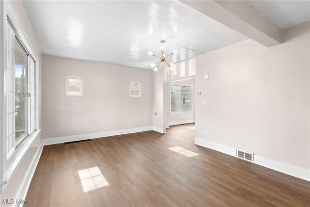 interior space featuring dark wood-type flooring, beam ceiling, and a notable chandelier