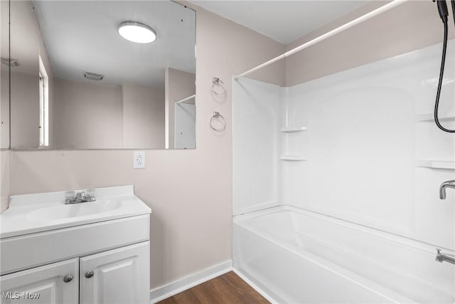 bathroom featuring hardwood / wood-style flooring, vanity, and  shower combination