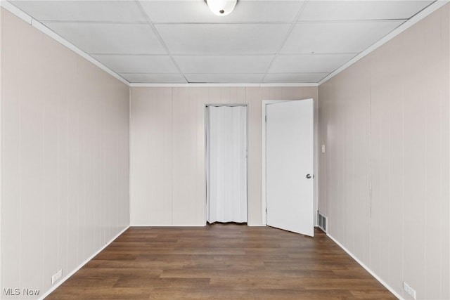 empty room featuring dark hardwood / wood-style flooring, crown molding, and a paneled ceiling