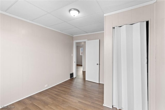 unfurnished room with a drop ceiling, crown molding, and wood-type flooring