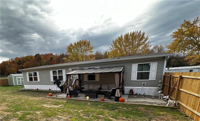 rear view of property with a yard, outdoor lounge area, a shed, and a patio area