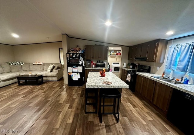 kitchen with vaulted ceiling, a kitchen island, hardwood / wood-style flooring, dark brown cabinetry, and black appliances