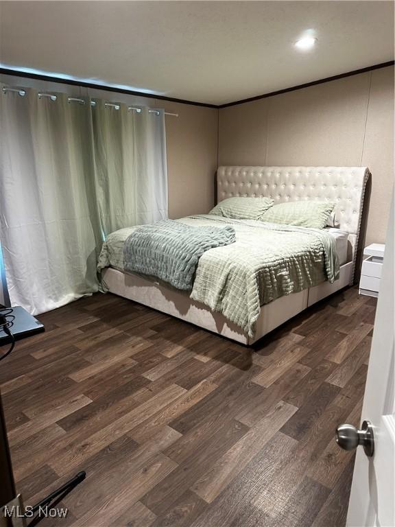 bedroom with crown molding and dark hardwood / wood-style flooring