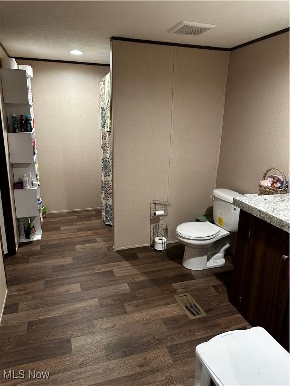bathroom featuring vanity, wood-type flooring, crown molding, and toilet