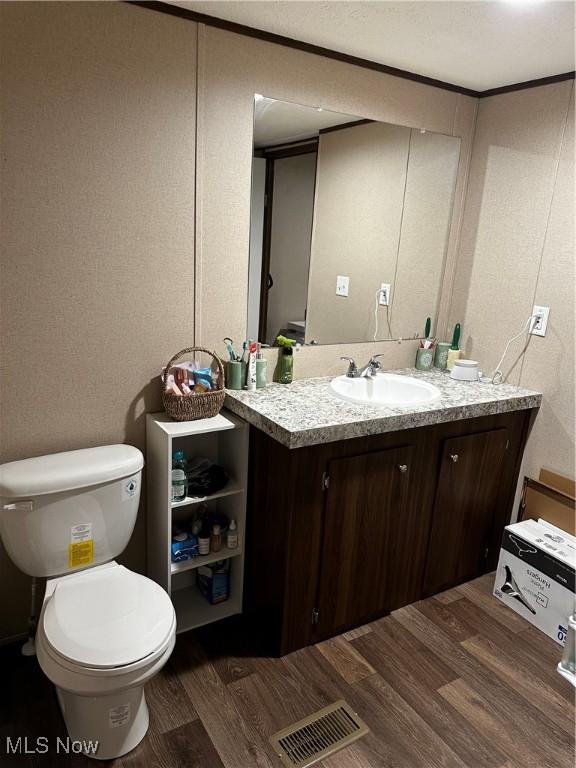 bathroom with vanity, hardwood / wood-style floors, crown molding, and toilet