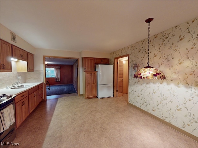 kitchen with hanging light fixtures, range with gas stovetop, sink, and white fridge