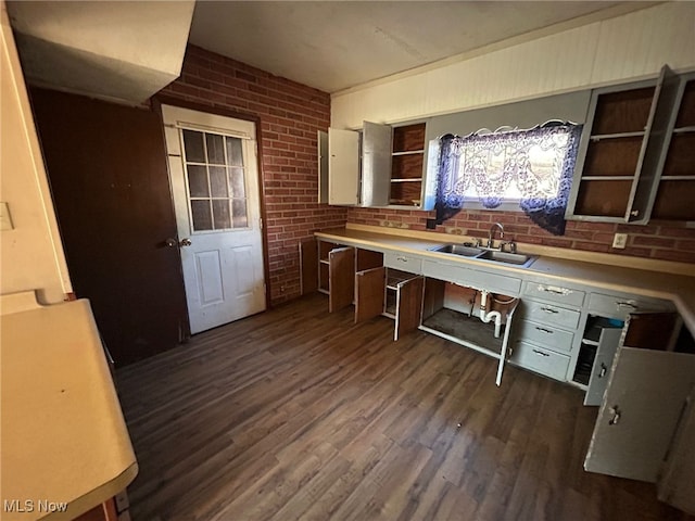 kitchen with white cabinetry, brick wall, dark hardwood / wood-style floors, and sink