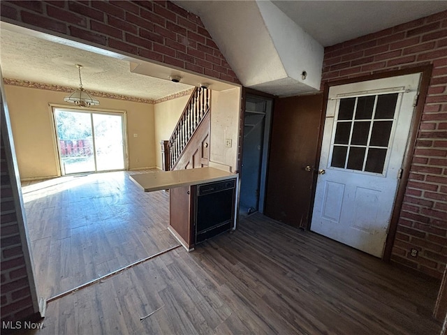 kitchen with brick wall, dark hardwood / wood-style floors, pendant lighting, a breakfast bar area, and kitchen peninsula