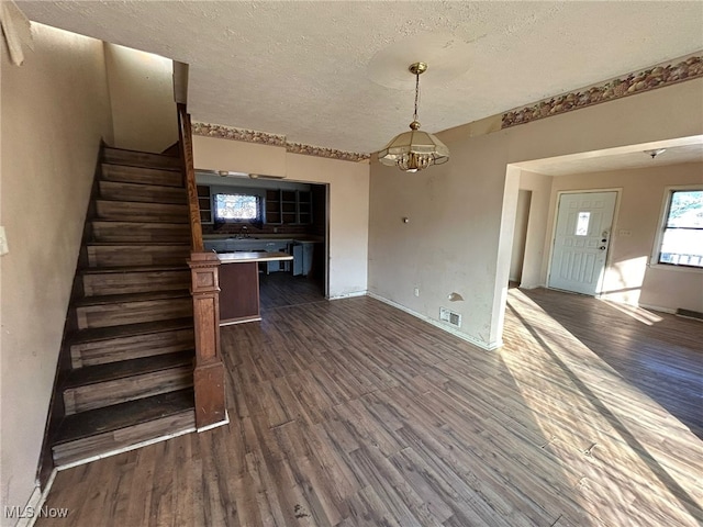 interior space featuring a notable chandelier, dark wood-type flooring, and a textured ceiling