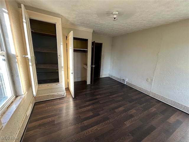 unfurnished bedroom with dark wood-type flooring, a textured ceiling, and a closet