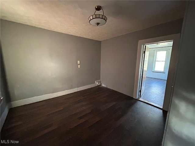 spare room with dark wood-type flooring and a textured ceiling