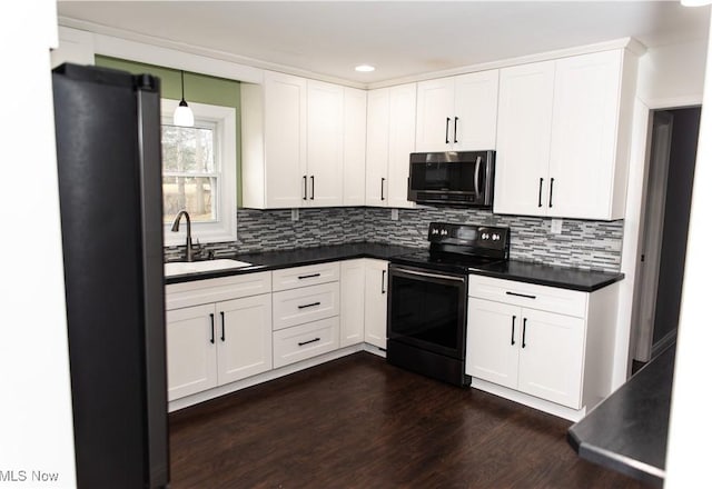 kitchen featuring sink, dark wood-type flooring, white cabinetry, hanging light fixtures, and stainless steel appliances