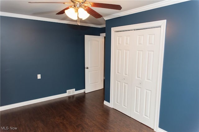 unfurnished bedroom featuring crown molding, dark wood-type flooring, ceiling fan, and a closet