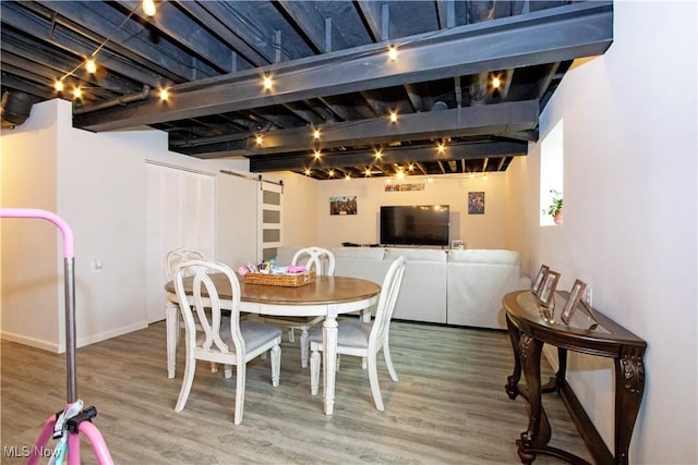 dining room with wood-type flooring, a barn door, and track lighting