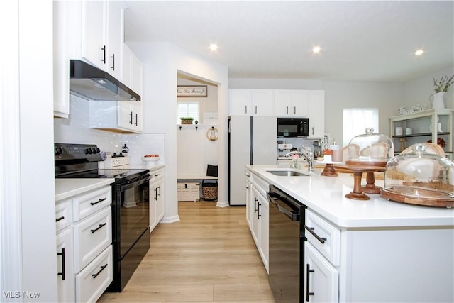 kitchen featuring sink, a center island with sink, white cabinets, and black appliances