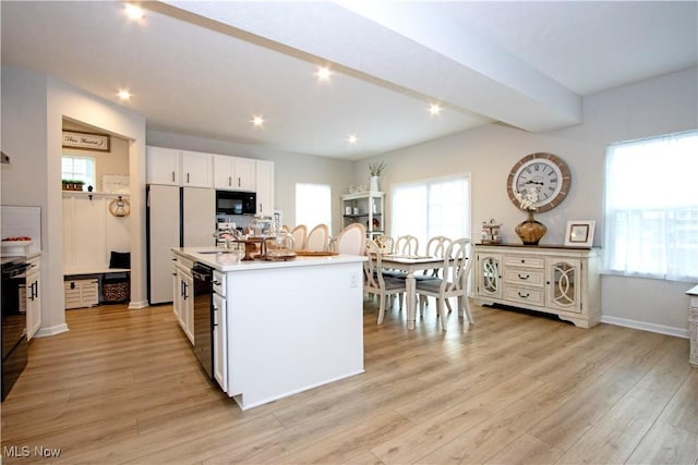 kitchen featuring a kitchen island with sink, white cabinetry, black appliances, and light hardwood / wood-style floors