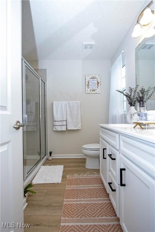 bathroom featuring vanity, wood-type flooring, an enclosed shower, and toilet