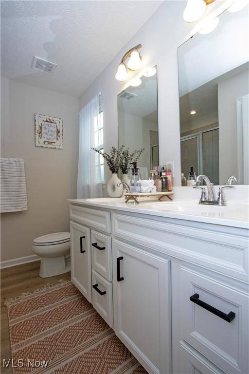 bathroom featuring walk in shower, vanity, toilet, and wood-type flooring