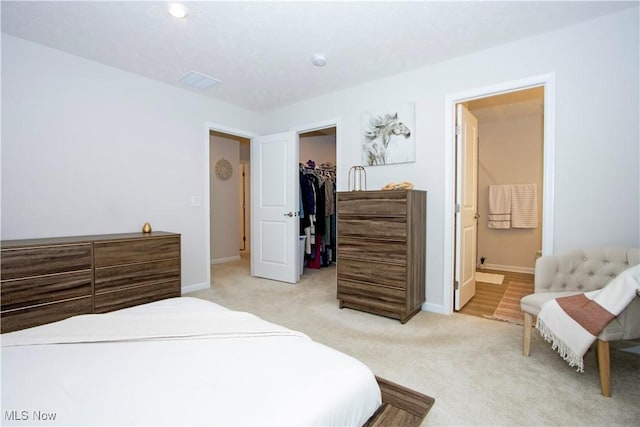 carpeted bedroom featuring connected bathroom, a spacious closet, and a closet