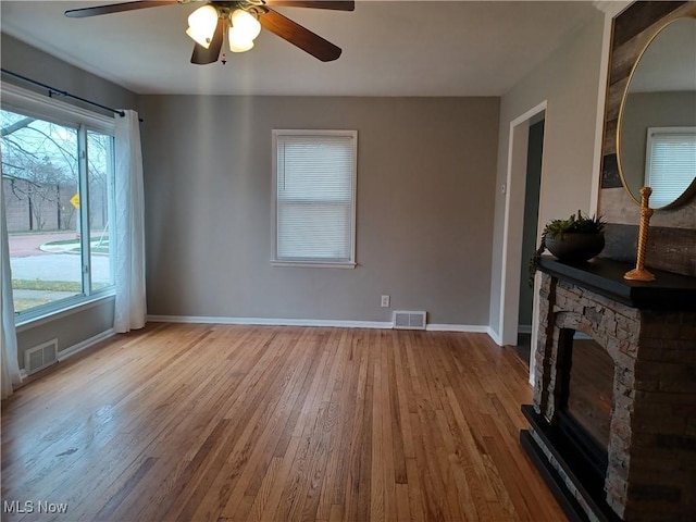 living room with ceiling fan, a fireplace, and light wood-type flooring